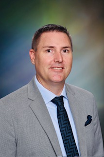A school portrait image of Josh Peete in a tie and grey jacket with a background that looks like the northern lights. 